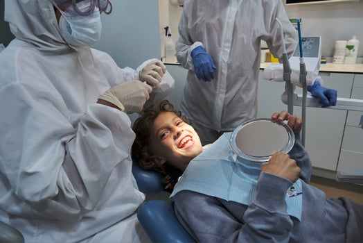 Dentist in medical uniform treating smiling boy in dental office photo