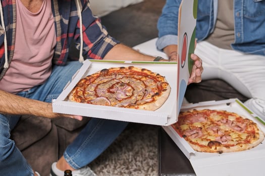 Crop men holding packages with pizza in living room photo