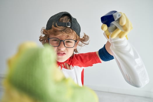 Curly boy in superhero clothes cleaning camera in studio photo