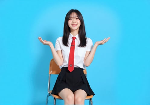 Asian girl in school uniform sitting on chair with hands outstretched photo