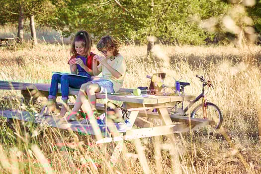 Cheerful children sitting on bench with book and sandwich photo