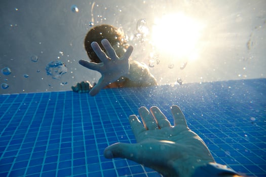 Unrecognizable boy and man reaching out hands in pool photo