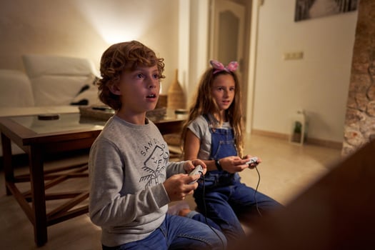 Perplexed children with gaming station sitting at living room photo