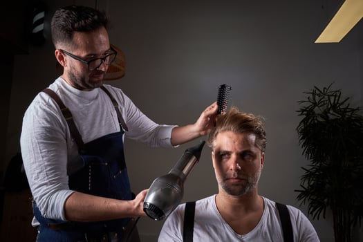 Concentrated barber drying hair of client photo