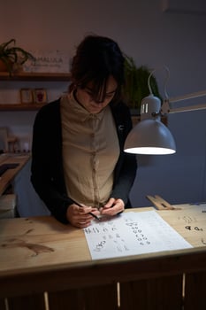 Focused female jeweler with ring and sketches at table photo
