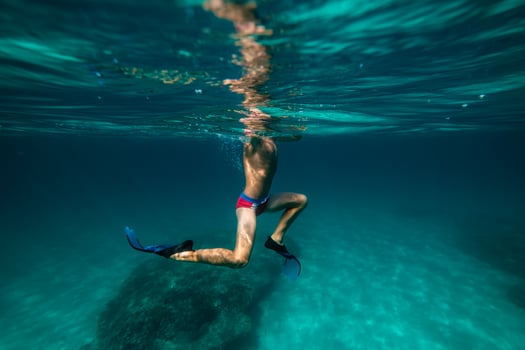 Boy in flippers swimming underwater in sea photo