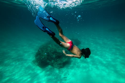 Teenager snorkeling in diving mask and fins observing sea bottom photo