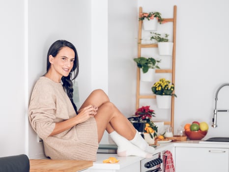 Smiling ethnic woman sitting on counterSide view full body of photo