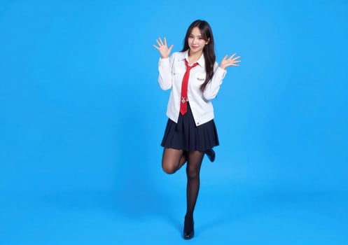 A young woman in a school uniform is posing on a blue background photo