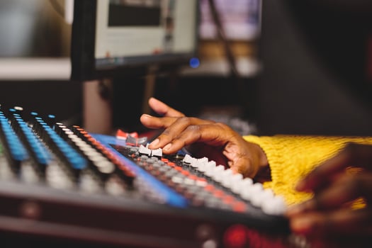 Crop ethnic female radio host using mixing console in studio photo