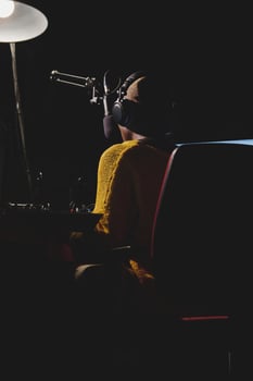 Unrecognizable ethnic woman in headset in dark broadcast studio photo