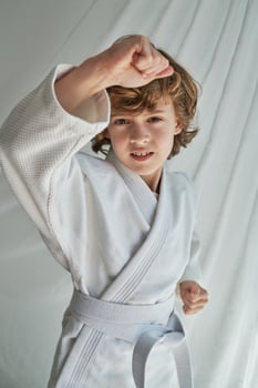 Serious boy in kimono doing karate photo