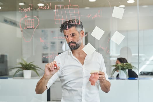 Serious ethnic man drawing scheme on glass board photo