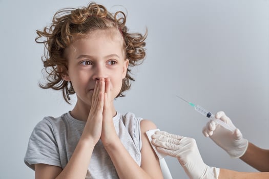 Faceless nurse vaccinating nervous child photo