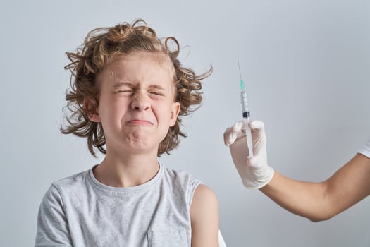 Boy closing eyes at syringe photo
