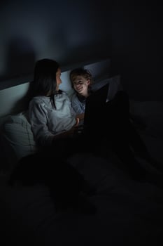 Mother and son watching film on tablet at night in bed photo