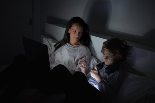 Mother and son watching film on laptop in dark room photo