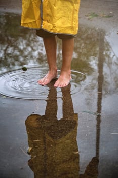 Unrecognizable child looking at reflection in puddle photo
