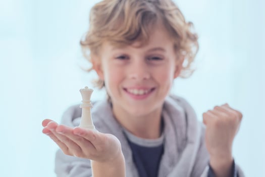 Smiling preteen boy with chess piece of queen on palm photo