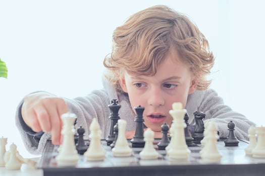 Serious preteen boy planning performing check during chess game photo