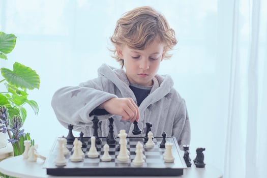 Focused preteen boy planning next move while playing chess photo