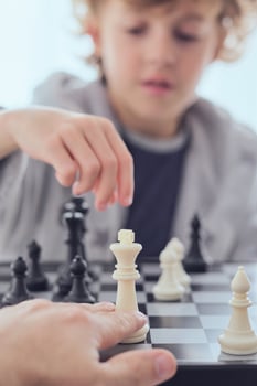 Anonymous person playing chess with boy photo