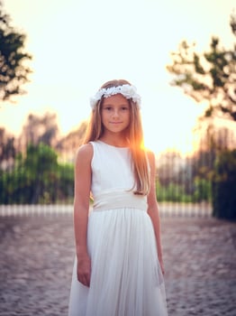 Smiling girl in white dress standing against sunset sky photo
