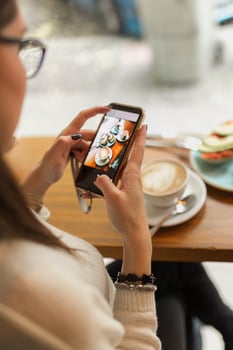 Crop woman taking photo of food in cafe