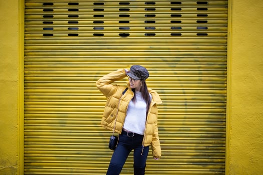 A woman in a yellow jacket standing in front of a yellow garage door photo