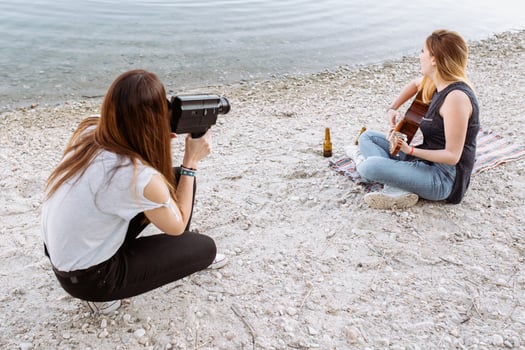Young woman shooting friend playing guitar photo