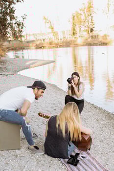 Three people sitting on the ground near a lake photo