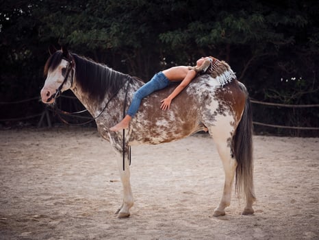 Young boy lying on brown horse with eyes closed in paddock photo