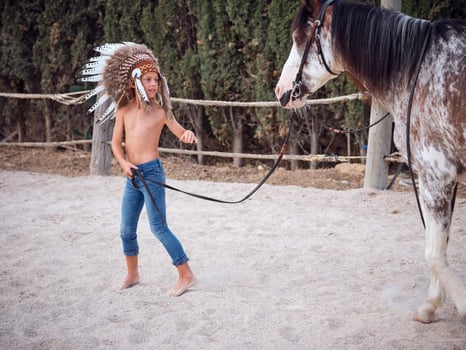 Happy kid in Indigenous roach headdress walking mare outdoors photo