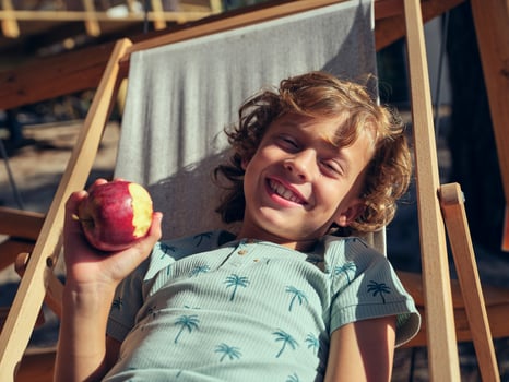 Happy boy eating apple on terrace photo
