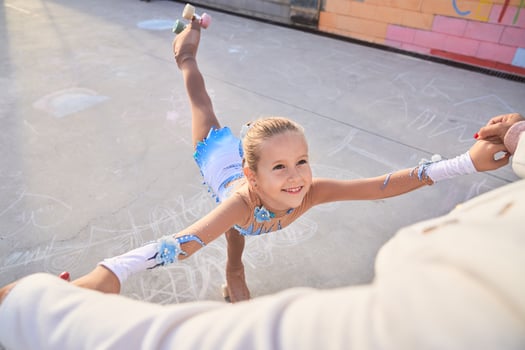 Cheerful girl in roller skates training with faceless trainer photo
