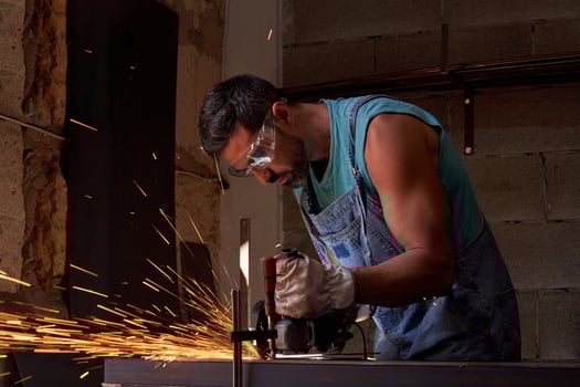 Focused male artisan cutting metal with disk grinder photo