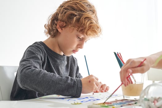 Focused boy painting with paintbrush photo