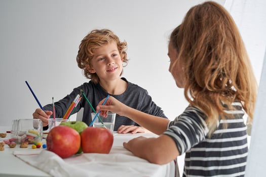 Boy painting near girl at table photo
