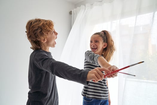 Joyful siblings playing in paintbrushes photo