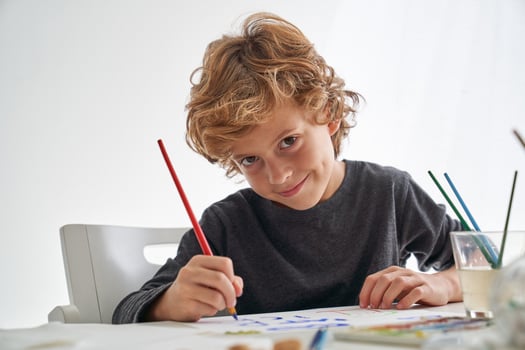 Cheerful boy painting at table photo