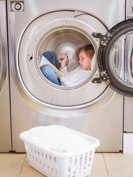 Concentrated boy reading book in laundry room photo