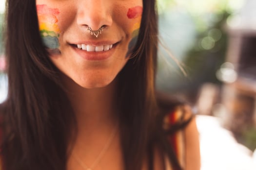 Brunette woman with LGBT symbol on face straightening hair photo