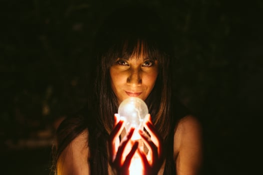 Thoughtful woman with burning lightbulb in darkness photo