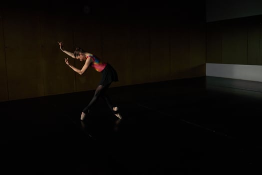 A woman in a black dress is dancing in a dark room photo