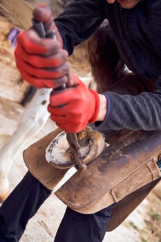 A man is using a hammer to make a hole in a piece of metal photo