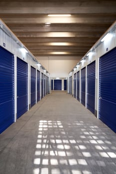A long hallway with blue doors in a storage unit photo