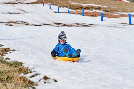 Positive boy sliding down snowy slope photo