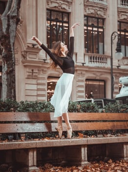 Gentle ballerina dancing on street bench photo