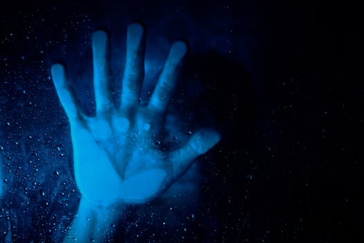 Anonymous hopeless person behind wet glass wall in neon light photo