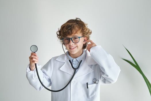 Smiling boy in medical uniform with stethoscope on white backgro photo